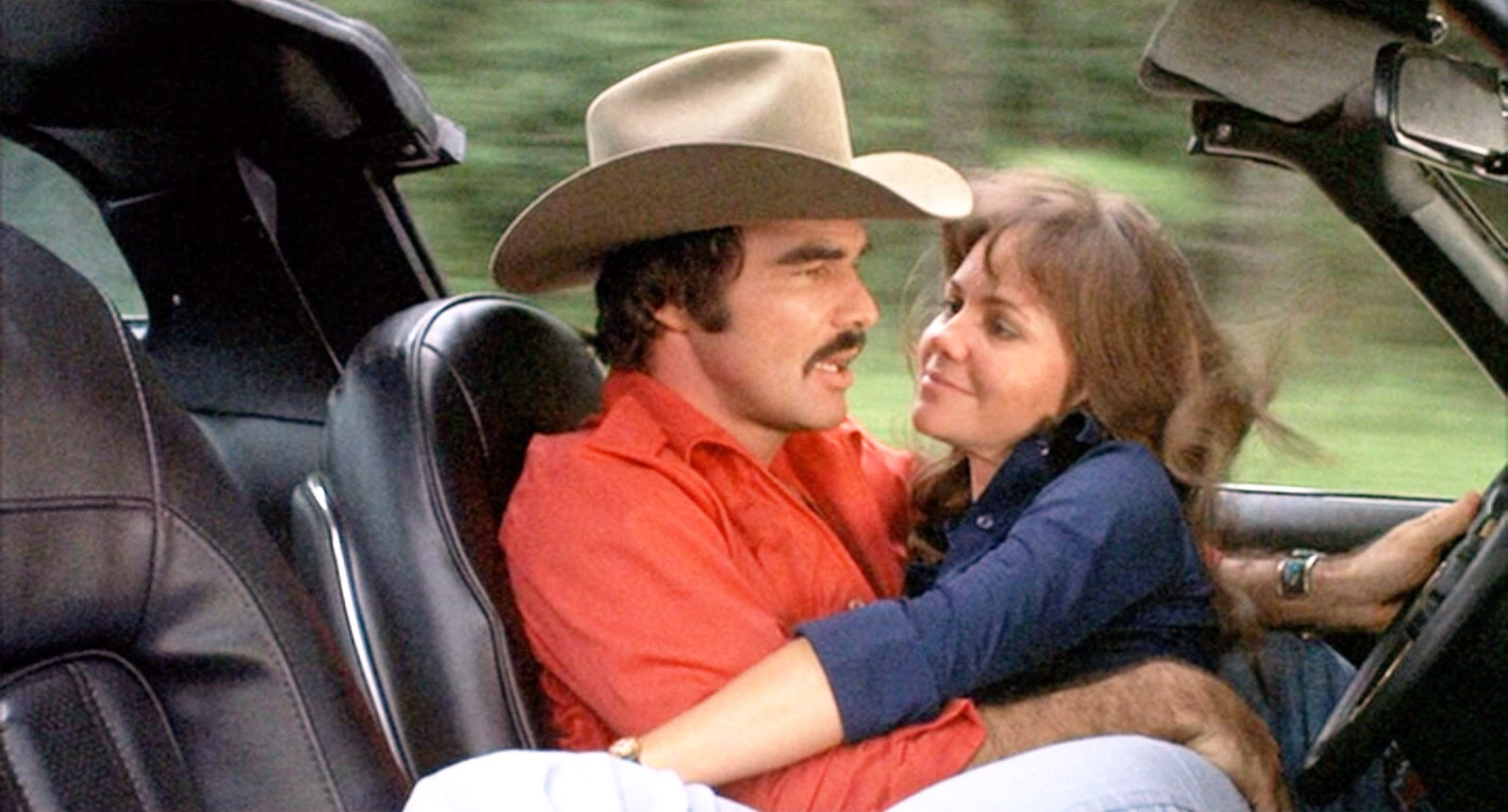 Frog (Sally Field) falls into the lap of The Bandit (Burt Reynolds) as they speed down the highway in a Pontiac Trans-Am
