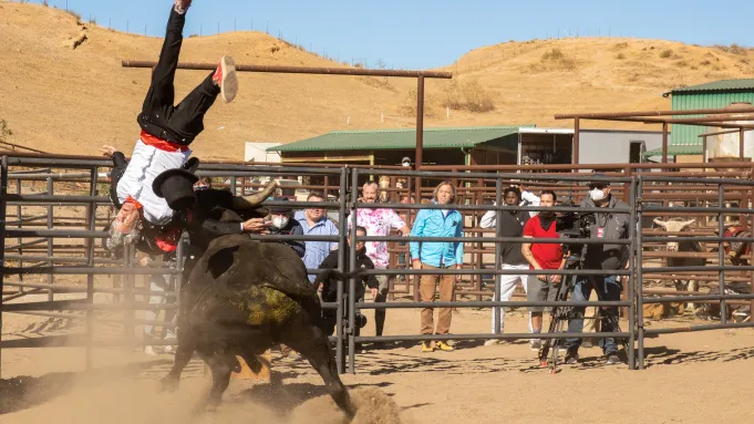 Johnny Knoxville is sent ass-over-teakettle by a charging bull while the Jackass crew watch.
