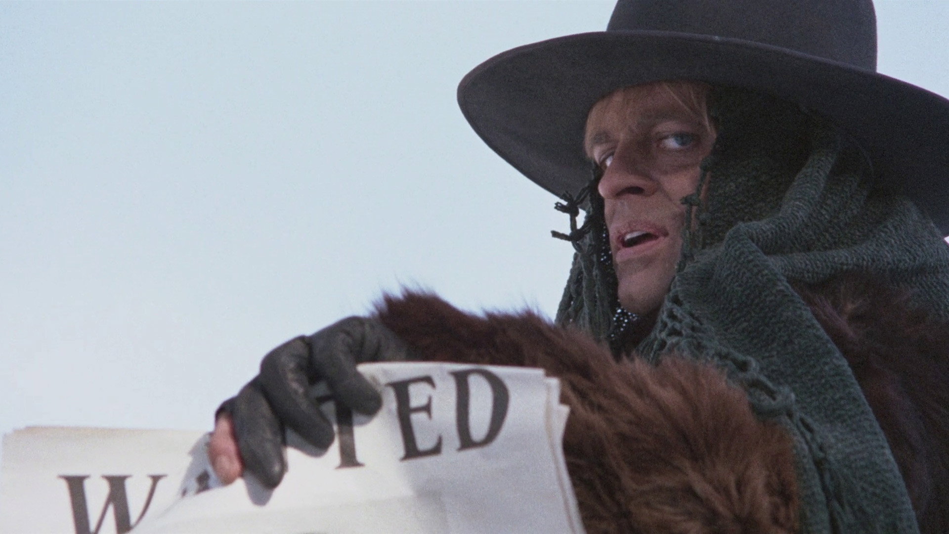 Klaus Kinski holds up a wanted poster in The Great Silence.