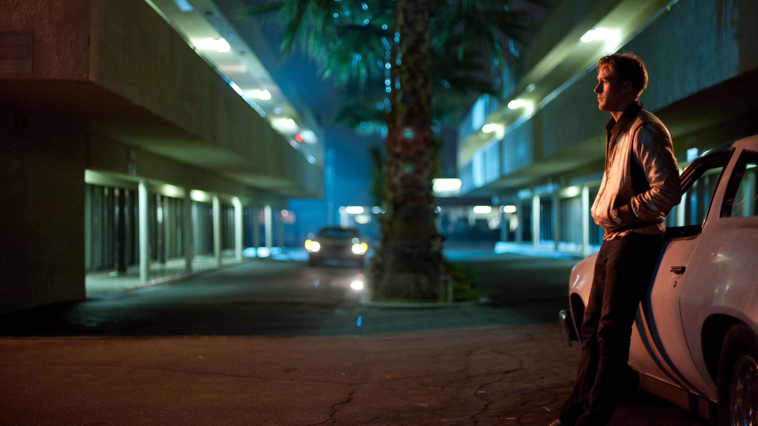 Ryan Gosling leans against his car in Drive.