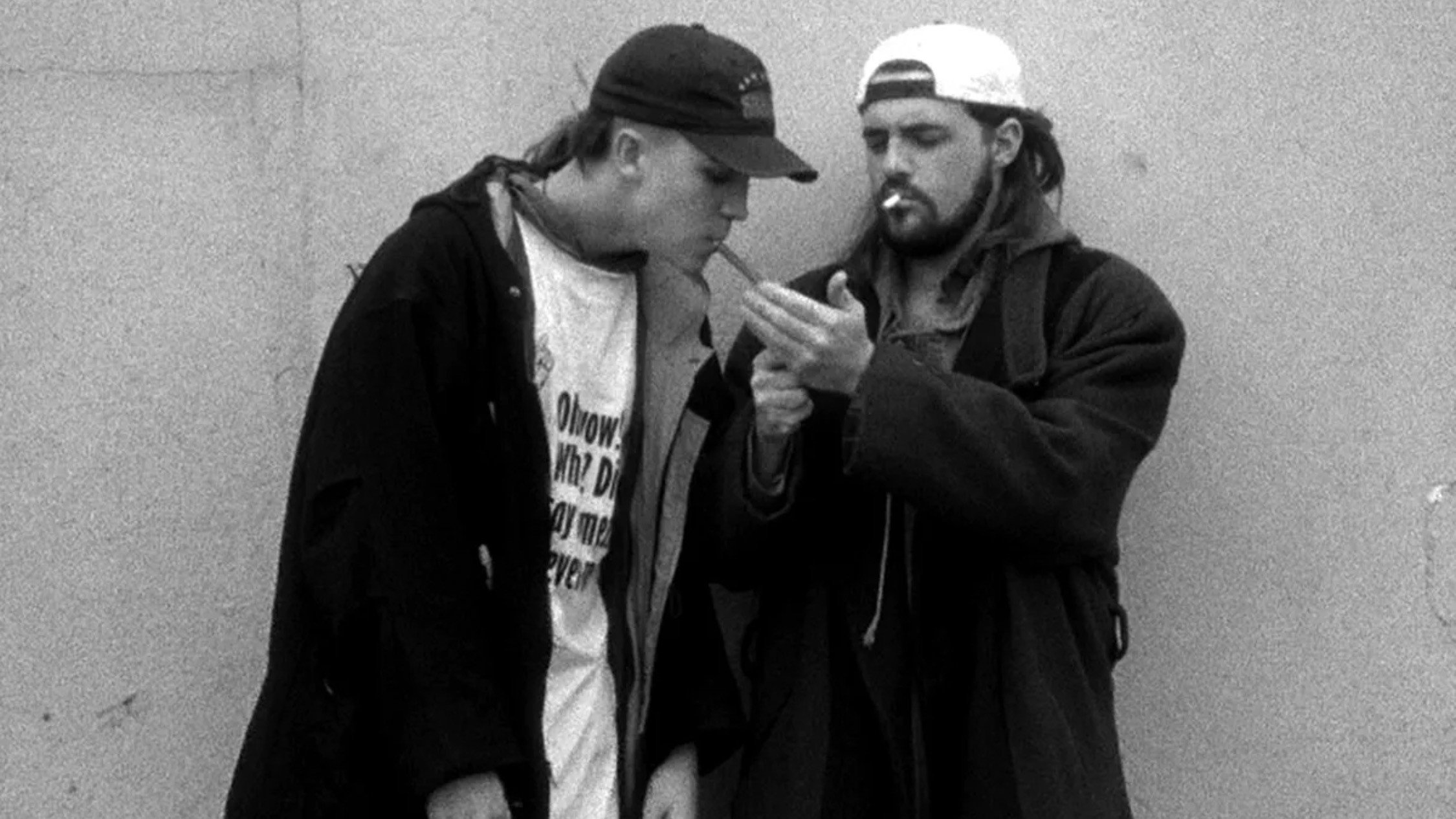 A cigarette-smoking Silent Bob lights his friend Jay's blunt.